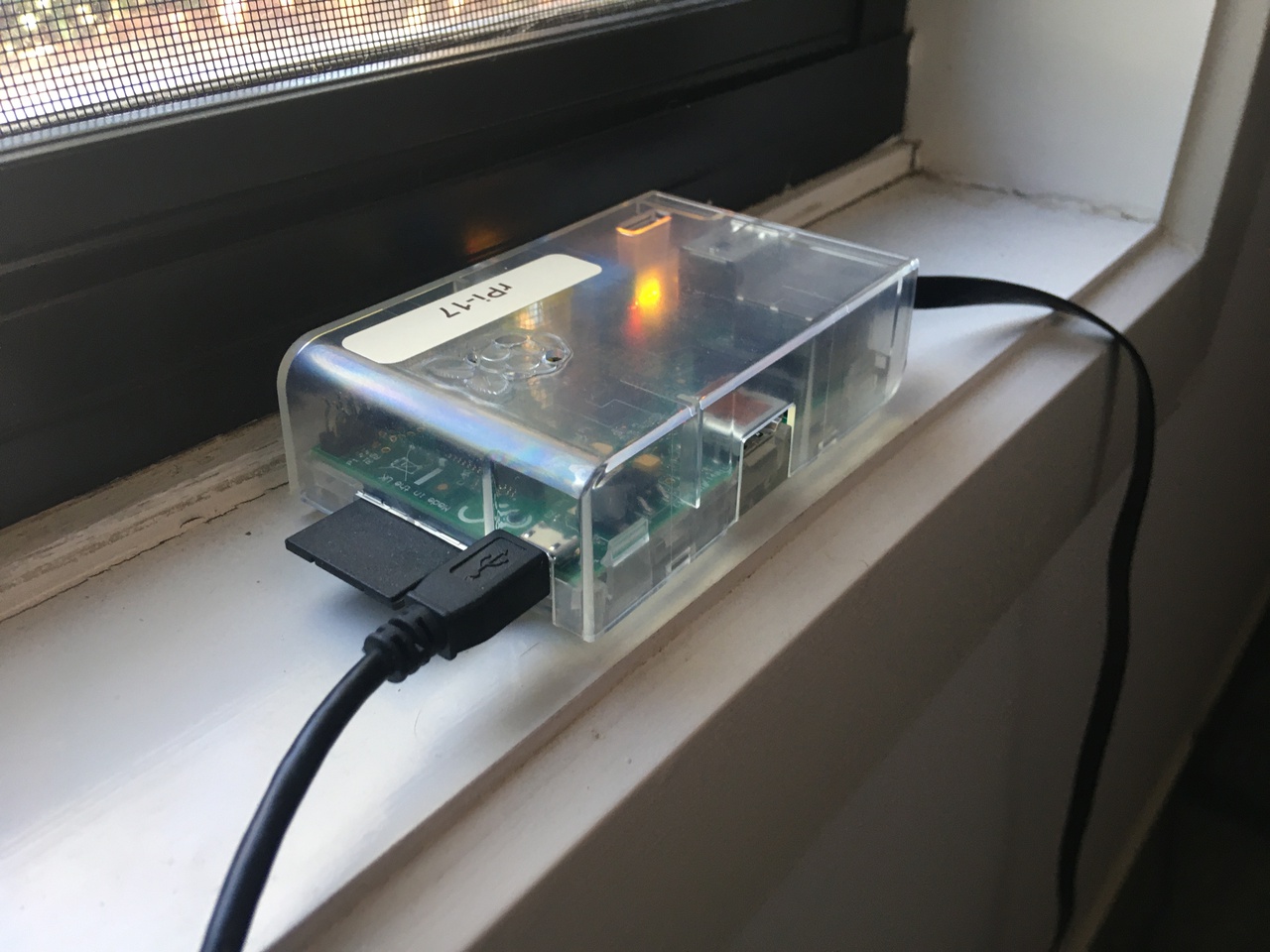 A small computer in a plastic case sitting on a windowsill