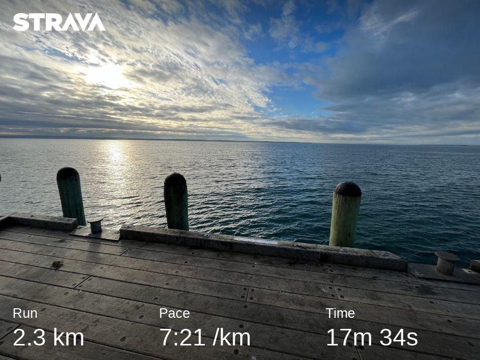Statistics from a Strava run overlaid on an ocean pier backdrop, 2.3km in 17 minutes 34 seconds